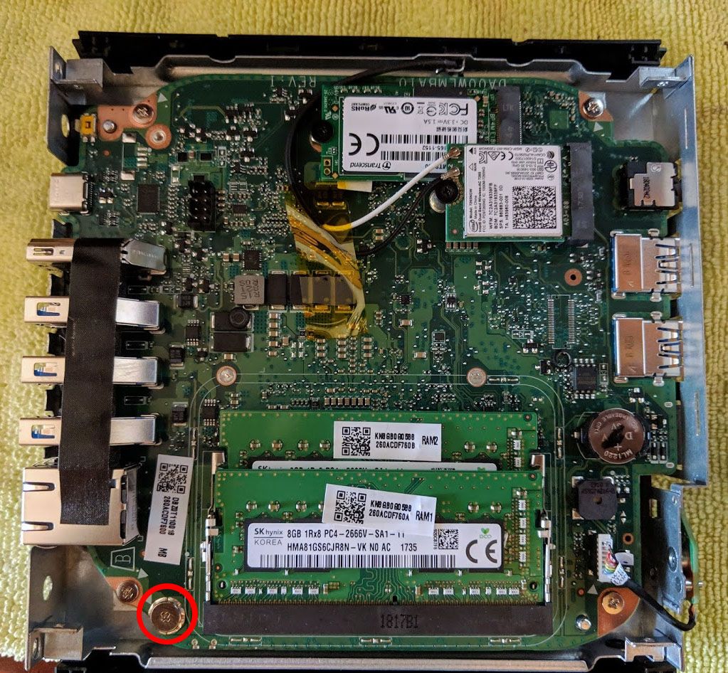 Материнська плата ASUS Chromebox 3 (CN65) зі знятою нижньою кришкою: два слоти памʼяті DDR4, SSD M.2 2242 і Wi-Fi-модуль. Червоним колом позначено гвинт захисту від запису в лівому нижньому куті біля слотів памʼяті.